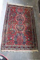 Full view of small Oriental rug showing overall pattern, colors, and fringed edges.