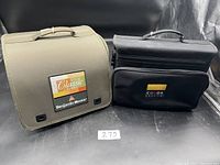 Two Benjamin Moore branded carrying cases, olive green and black, with color samples inside shown from front