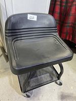 Front view of the Craftsman mechanics chair showing the black molded plastic seat and backrest, with a white lot number sticker on top.