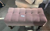 Side angle showing pink tufted upholstery, nailhead trim, and cabriole legs on decorative bench