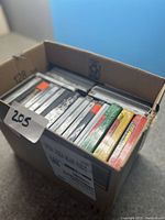 Full box of DVD movies arranged upright, showing their spines and front covers in a cardboard box.