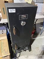 Full view of the upright black Masterbuilt Pro smoker showing the exterior with temperature gauge and wooden handle on door.