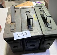 Top view of three military ammunition cans placed next to each other, showing metal handles and latches, with a lot tag '295'.