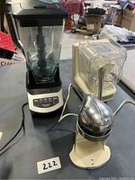 Ninja Professional 1000 blender, white plastic food processor, and Juice-O-Mat juicer shown from front angle on table.