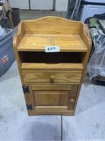Front view of wooden side table showing open shelf, drawer closed, and cabinet door closed.