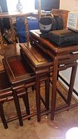 Four cherry wood nesting tables stacked together showing the polished finish and straight wooden legs.
