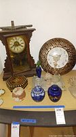 Overview of mantle clock, wall clock, perfume bottles, and decorative box on table.