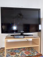 Front view of Samsung 40 inch TV on wood stand with remote in front.