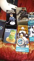 Photo showing boxed bobbleheads of San Jose Sharks players including Logan Couture and Patrick Marleau, along with a Chia Pet shaped with a green plant beard and mini locker collectibles.