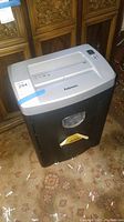 Fellowes paper shredder on carpet with shredded paper around it
