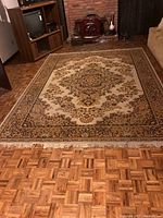 Full view of large area rug on parquet floor, showing overall pattern and condition including fringe damage.