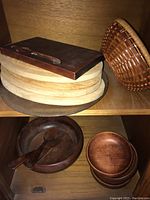 Wooden salad bowl with serving utensils, stacked wooden bowls, wooden cutting boards, rectangular board, glass platter, and wicker basket.