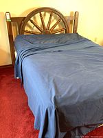 Wooden bed frame with ship's wheel headboard and blue bedding, metal side rails with casters