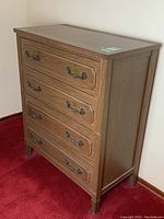 Side angled view showing full dresser, wood grain, metal handles, and leg base.