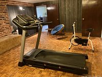 Full view of black HealthRider treadmill on parquet floor with basement wall behind