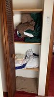 Photo of closet shelves containing folded bath, hand, and tea towels in colors like green, brown, maroon, and white.