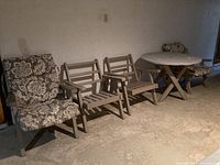 Overview of patio set showing wooden round table and four wooden chairs, two with floral cushions.