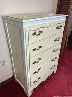 Side angled view of the dresser showing painted wooden frame and top surface details.
