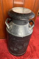 Front view of black metal milk can with lid and dual handles