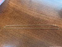 Full length of gold chain laid flat on wood surface