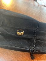 Ring resting on black velour pouch, full front view.