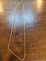 Full view of 18K gold chain necklace laid on wood surface