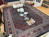 Full view of rug laid on hardwood floor with assorted dishes and tableware