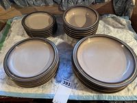 Four stacks of round beige stoneware plates and bowls on fabric backing