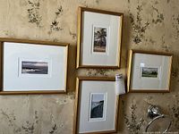 Four framed landscape prints hung on wallpapered wall