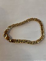 Full view of the 10K gold curb link bracelet laid flat