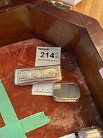 Both silver pill boxes on red velvet tray, showing relative size