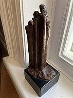 Front left angle view showing the full bronze sculpture with elongated abstract figures on black base