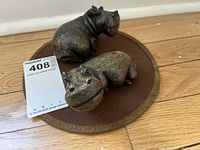 Two hippo figurines on a round brown pad
