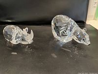 Faceted Swarovski rhinoceros and bear figurines displayed side by side on dark surface