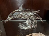 Side profile view of clear crystal dolphin figurine on wave-shaped base