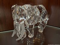 Front-right angle view of the clear crystal elephant figurine on wood backdrop
