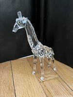 Front three-quarter view of crystal giraffe on wood floor with black backdrop