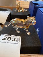 Front three-quarter view of amber crystal tiger cub on black foam pad with MaxSold tag