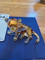 Front-left view of amber and clear crystal tiger cub on blue SCS box with auction tag