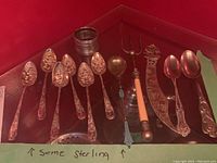 Group of ornate floral spoons, small ladle, hors d'oeuvre fork, decorative letter opener and serving spoons arranged in display