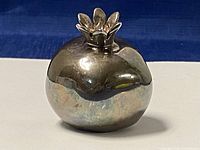 Front view of the sterling silver pomegranate paperweight showing detailed crown top and smooth polished finish with reflective surface.