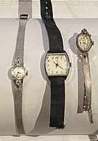 Three vintage ladies watches displayed showing overall lot contents. Left is silver-tone BERTMAR 17 jewel 10KT rolled gold plate watch with mesh band, center is rectangular face watch with black strap, right is small oval face watch with metal band.