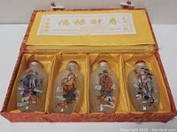 Photo of four Chinese snuff bottles in original fitted fabric box with silk lining and paper insert
