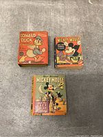 Three vintage Disney Big Little Books in used condition on a gray surface.