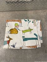 Folded shower curtain fabric showing colorful cartoon-style animal illustrations.