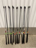 Full view of 12 golf shafts standing upright showing grips and shaft lengths.