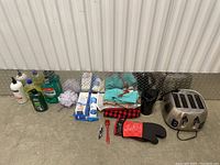 Photo showing a collection of kitchen and cleaning items including a stainless steel toaster, cleaning liquids, microfiber cloths, a coffee pot, and an oven mitt.