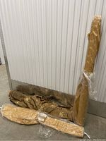 Three large fabric rolls on floor against metal wall section