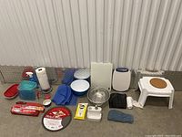Wide shot showing all items in lot including bowls, containers, baking supplies, stool, cleaning spray, towels, scale.