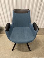 Front view of blue fabric office chair with black leather accents on backrest and armrests.